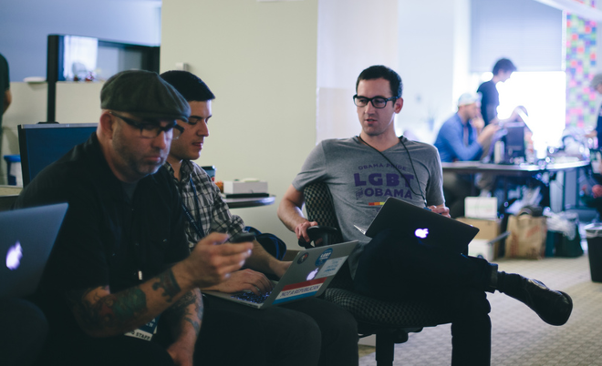 a group of men sitting at a table with laptops