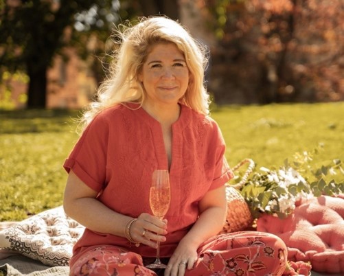 a woman sitting on a blanket holding a wine glass