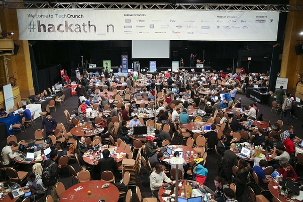 a large group of people sitting at tables in a room with a large banner